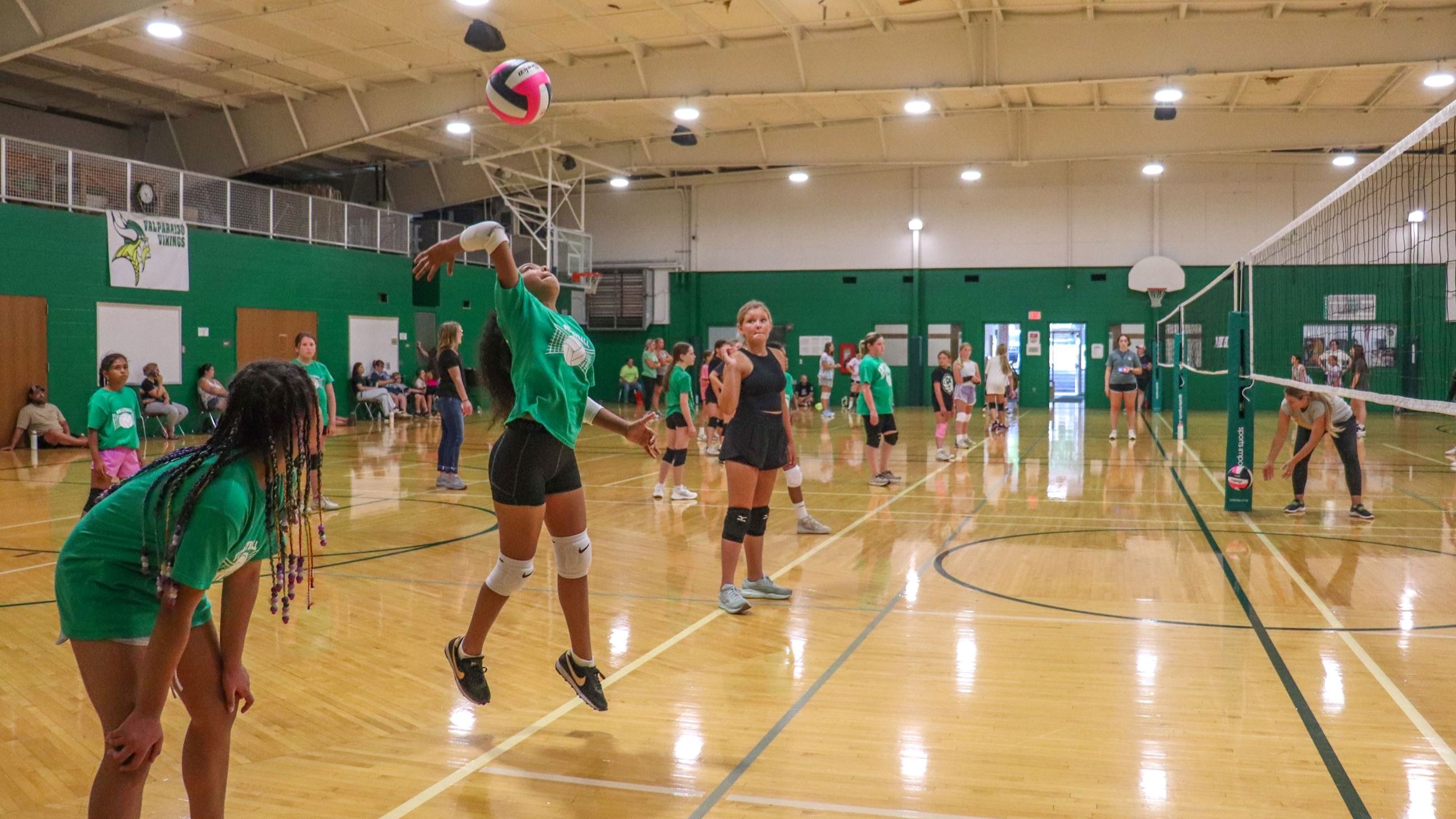 Player jumping to hit a volleyball in a school gym