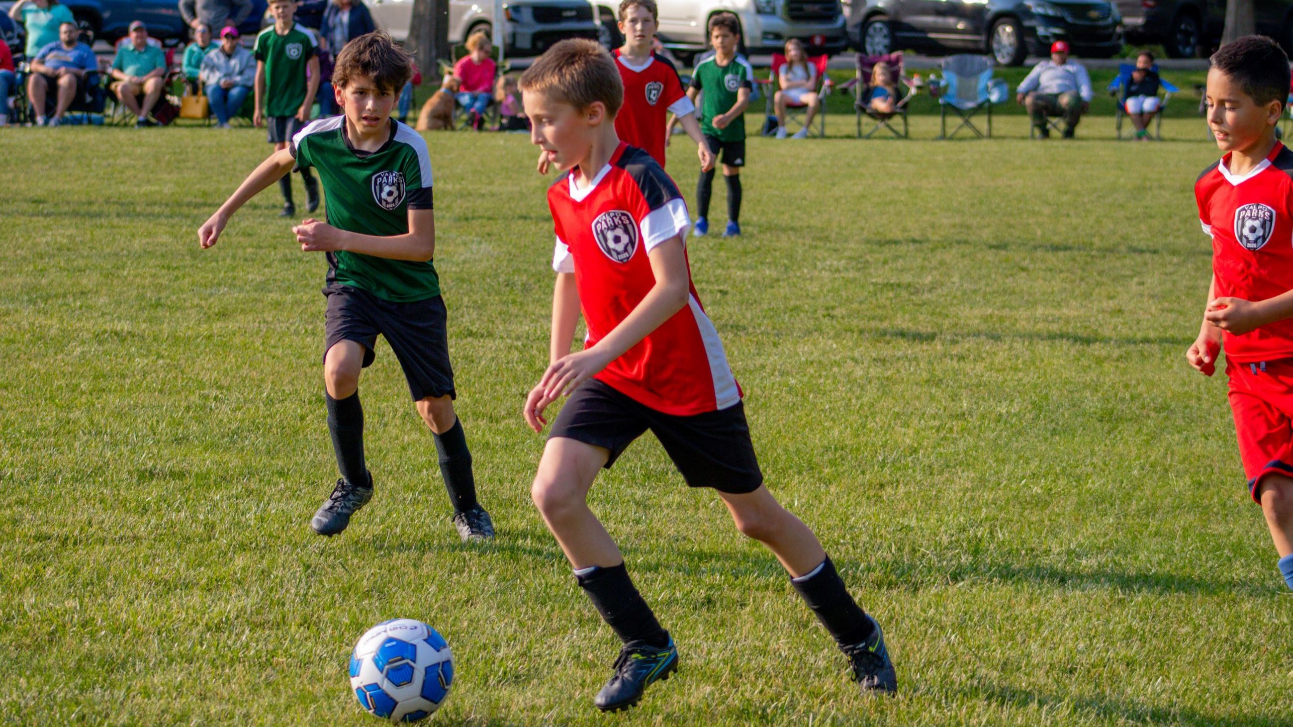 Close up of 3 kids playing a soccer game