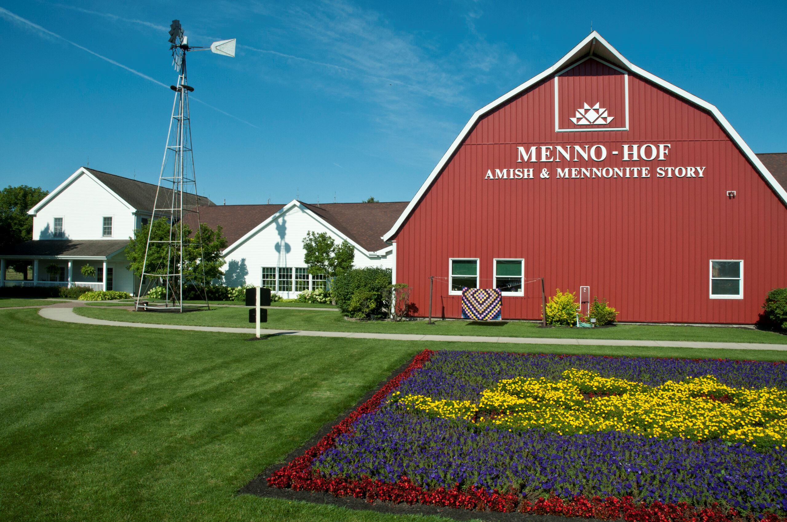 photo of the exterior of Menno-Hof, which looks like the side of a barn with a flower patch in front