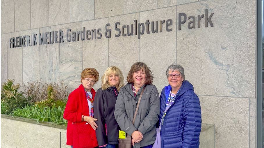 Women standing in front of a building reading Frederik Meijer Gardens & Sculpture Park